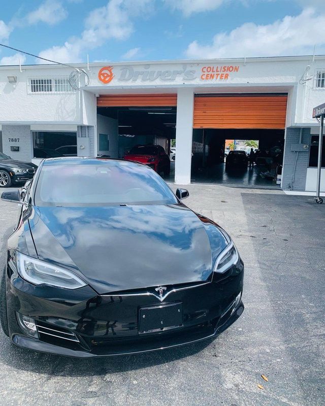 Black Tesla in front of the Driver's Collision Center shop
